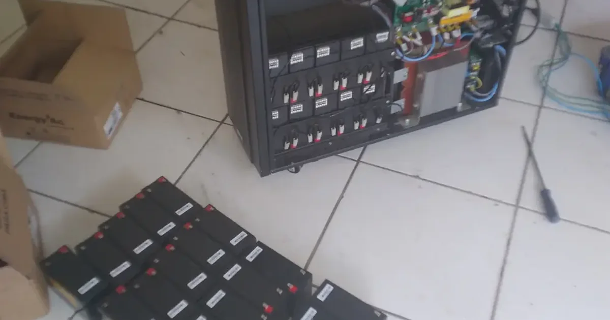 Banco de baterias retirado de um nobreak durante a troca, ao lado do equipamento aberto
